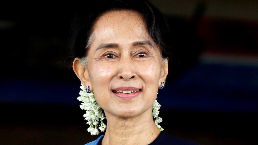 Aung San Suu Kyi smiling with white flowers in her hair