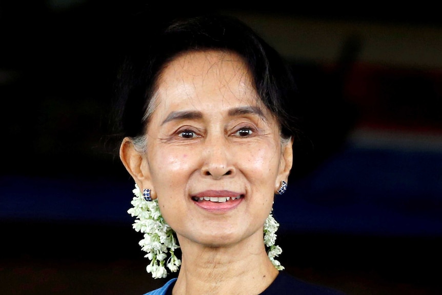 Aung San Suu Kyi smiling with white flowers in her hair