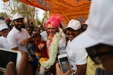 Pat Farmer laden with garlands of flowers and wearing a pink turban among supporters.