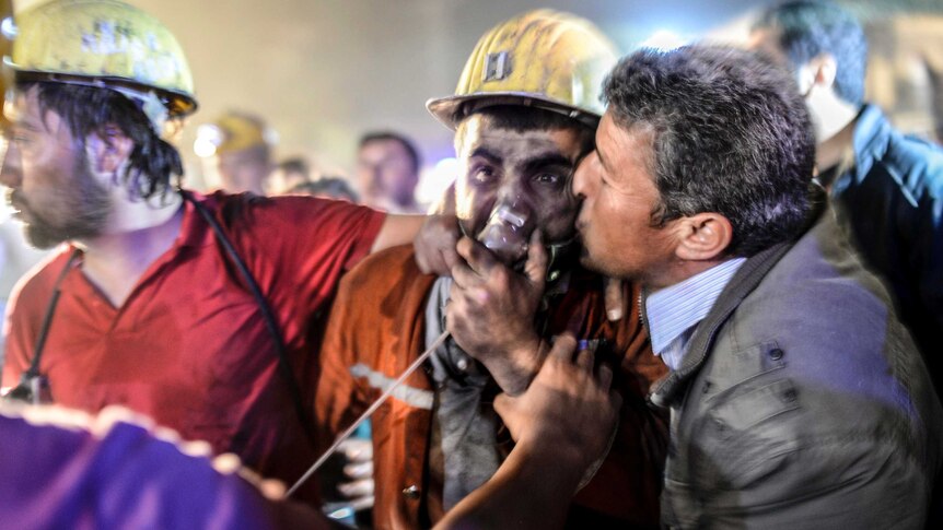 A miner celebrates with his father (R) after an explosion and mine collapse in Manisaon.