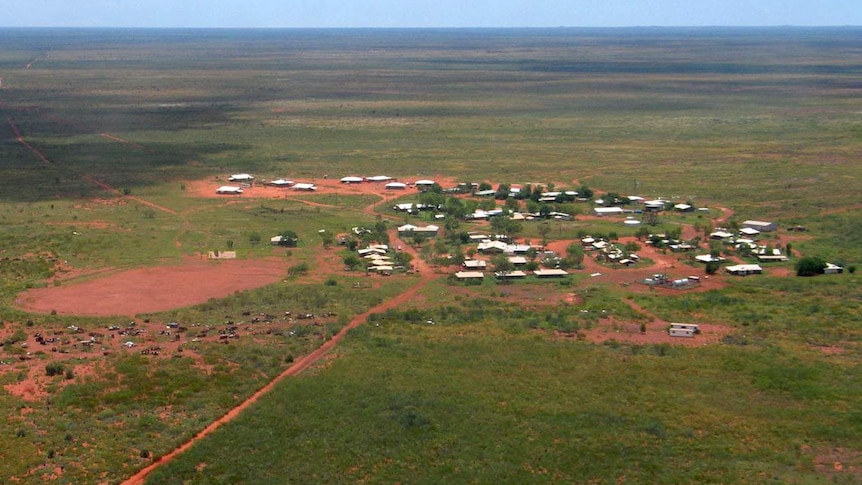 An aerial view of a remote outcrop of buildings amid a dusty arid landscape.
