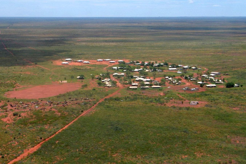 An aerial view of a remote outcrop of buildings amid a dusty arid landscape.