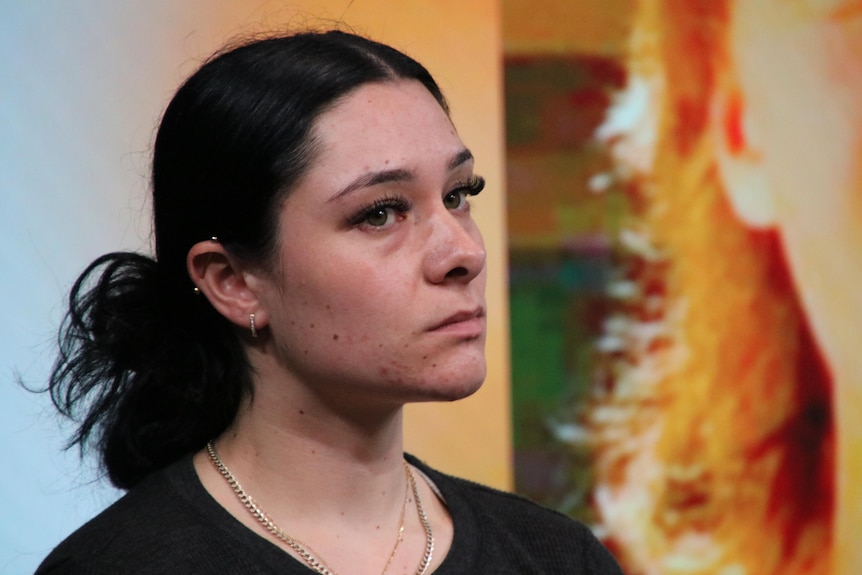 A young woman with dark hair looks sad at a press conference.