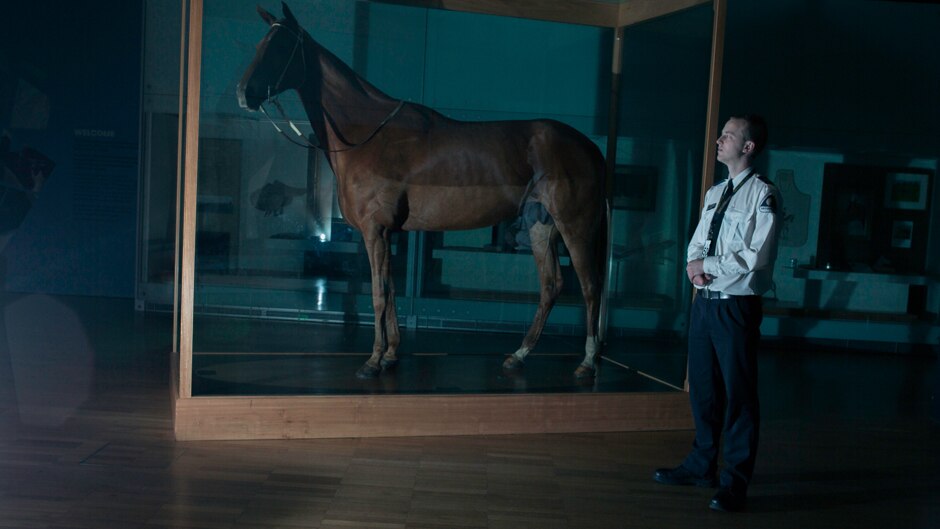 Melbourne Museum night guard Maximillian Gustew stands next to Phar Lap.