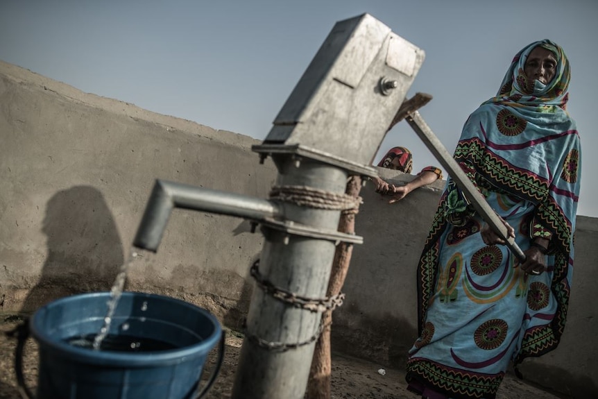 A woman is getting water from the well.