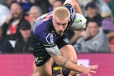Melbourne Storm's Cameron Munster runs with the ball over the Penrith Panthers' Stephen Crichton.