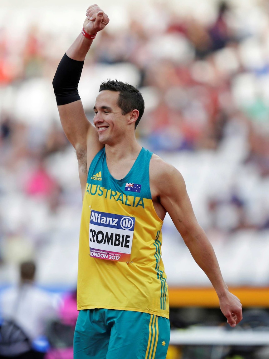 Cameron Crombie holds up his right arm with a smile on his face at World Para Athletics Championships.
