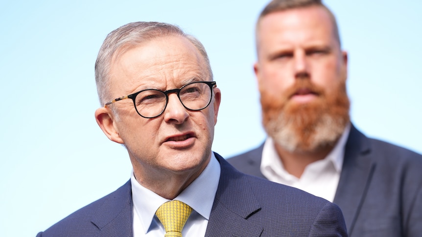 Anthony Albanese in focus wearing a suit and yellow tie and Hunter candidate Dan Repacholi standing behind him