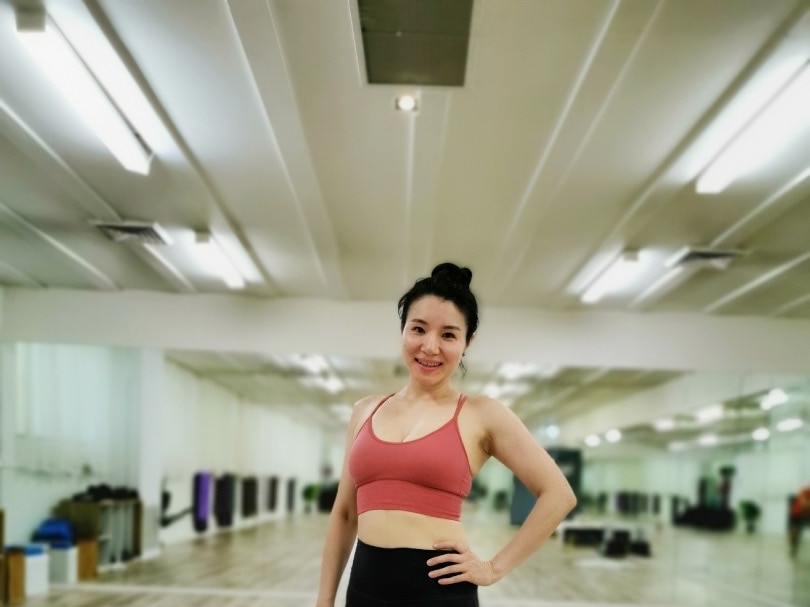 Helen Li, dressed in activewear, smiles inside her yoga studio.