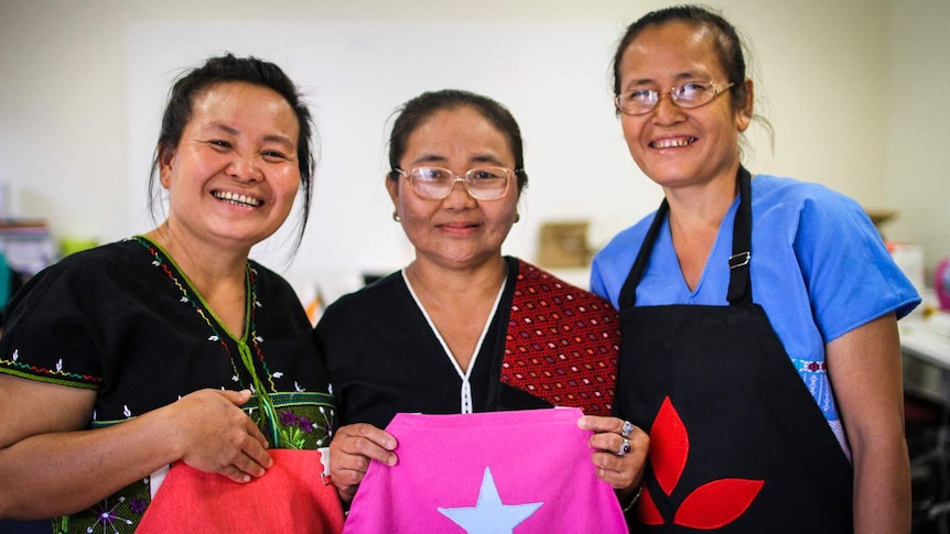 Three Karen refugees from Nhill proudly displaying the aprons they created in their sewing class.