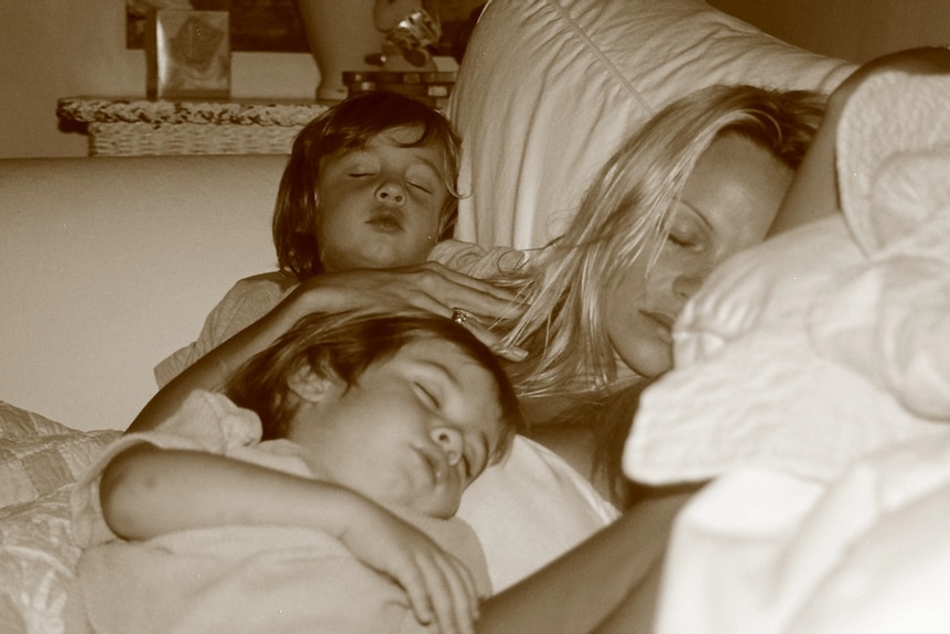 Pamela Anderson asleep in bed with her two infant songs, also asleep