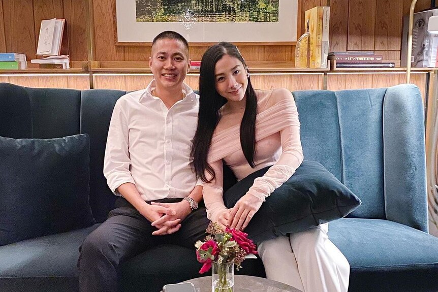 Un homme thaïlandais et une femme thaïlandaise s'assoient ensemble souriant sur un canapé 