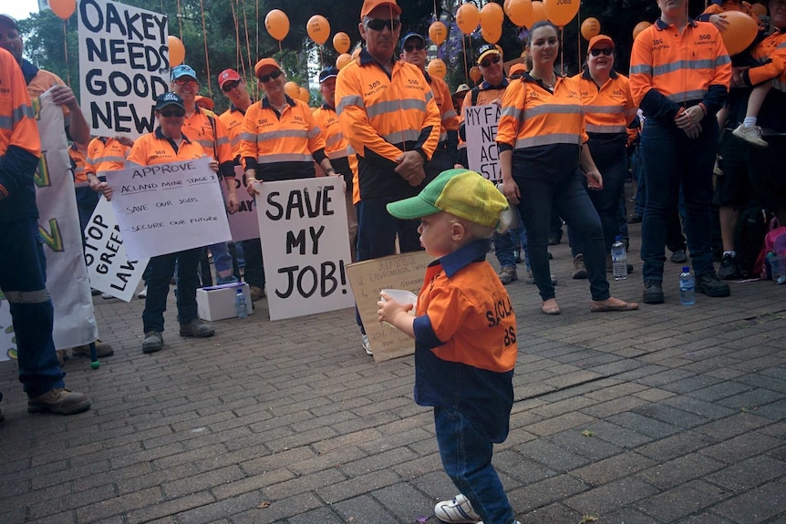 A group of protesters outside a mine with a small boy in a cap