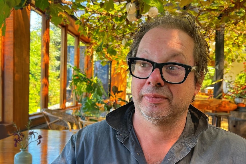 David Feldheim sitting in a large sunny room by a wooden table