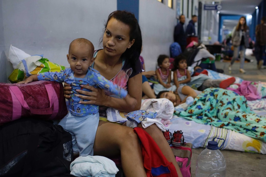 Venezuela migrant and her son are seen along with other children sitting in the street at the  border of Peru and Ecuador.