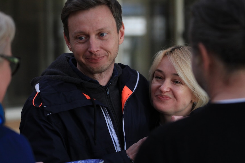 Man and woman speaking to two other people with smiles on their faces.