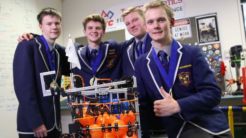 High school students standing in a row a round a robot they built