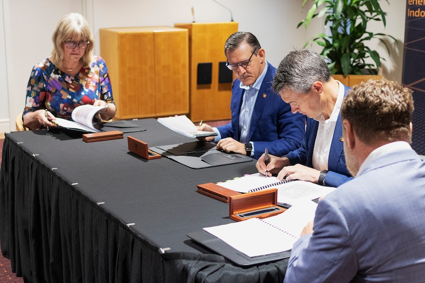 Four people at a table sign a development agreement.