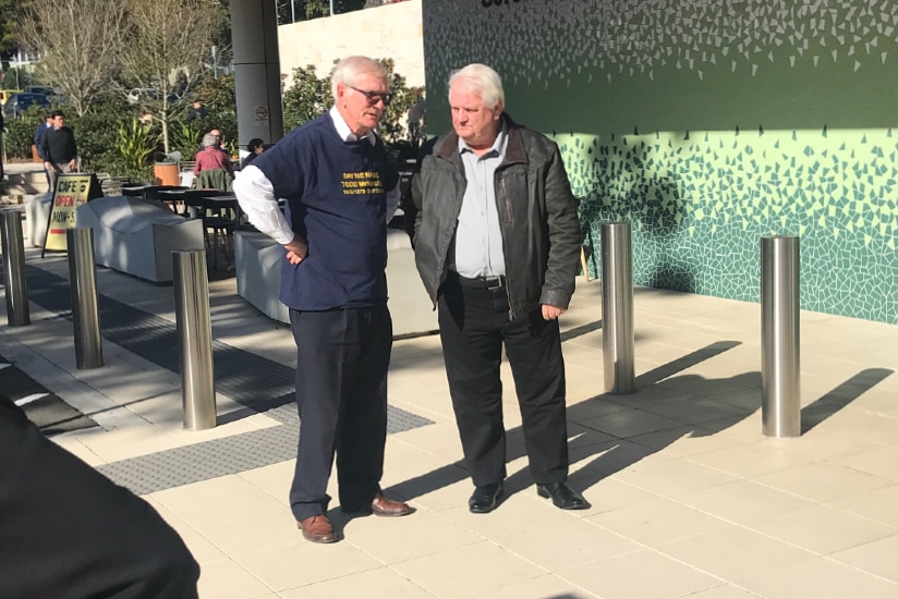 two men standing outside a coroners court talking
