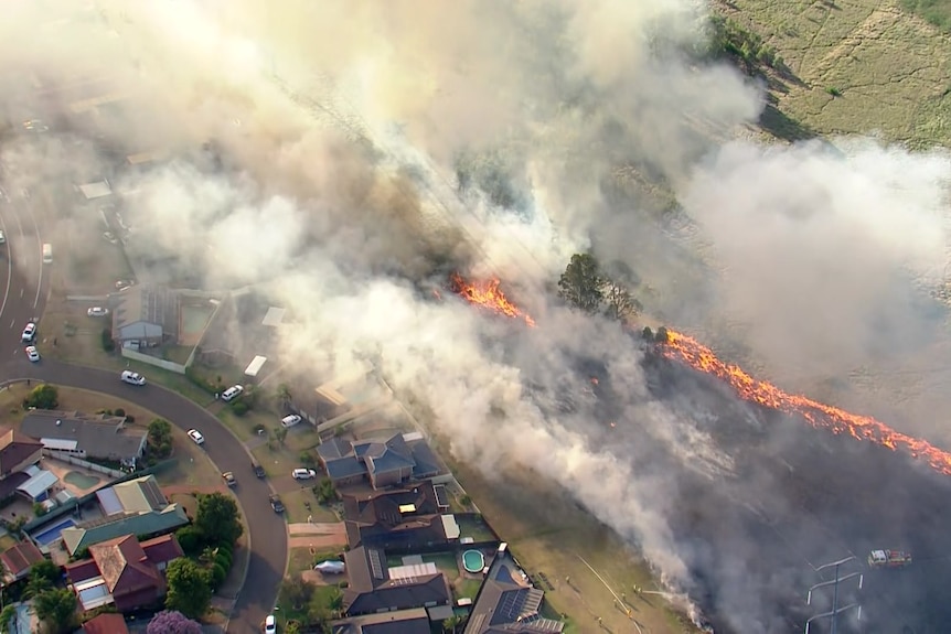 A grassfire burning next to homes