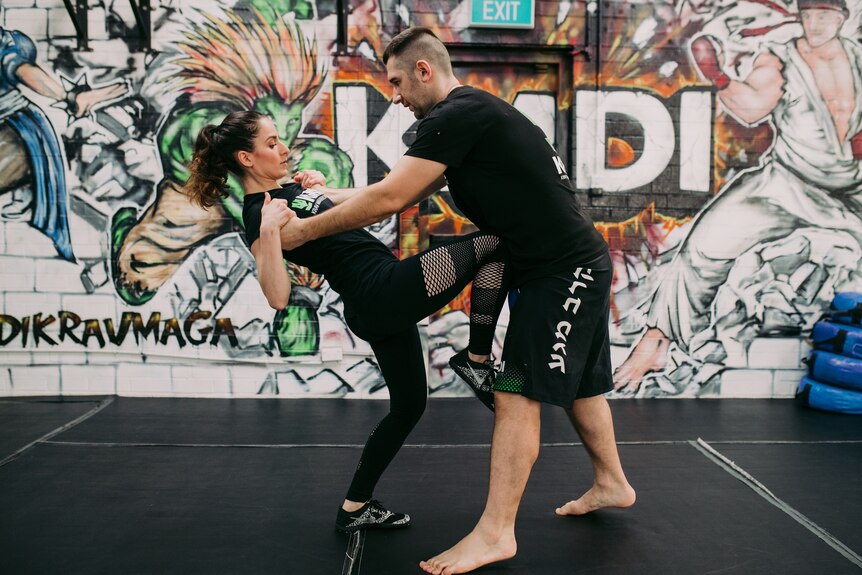A woman demonstrates a self-defence move on a man.