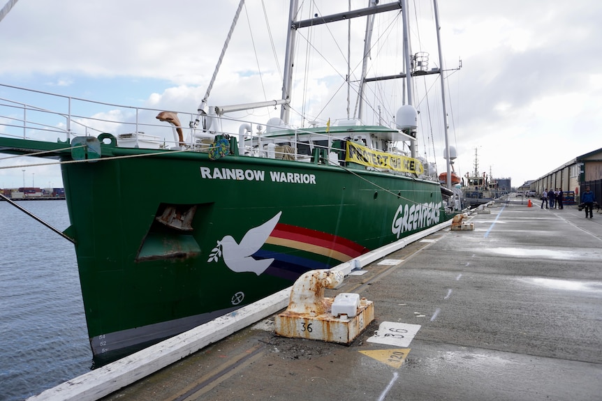 A big ship with the name Rainbow Warrior docked in a port