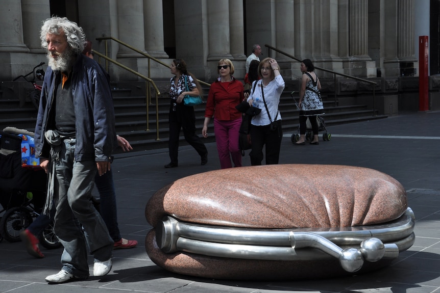 A homeless man walks through the central Melbourne's Bourke St.