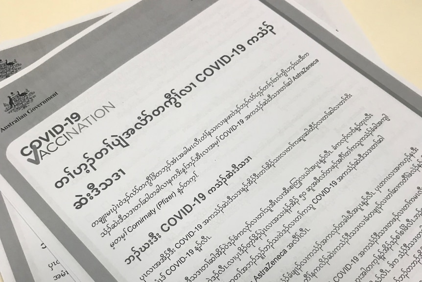 A piece of paper shows covid-19 vaccination information in the Karen language.