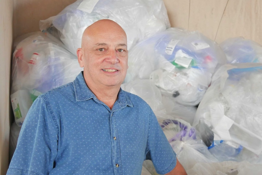 man stands in front of soft plastic bag waste