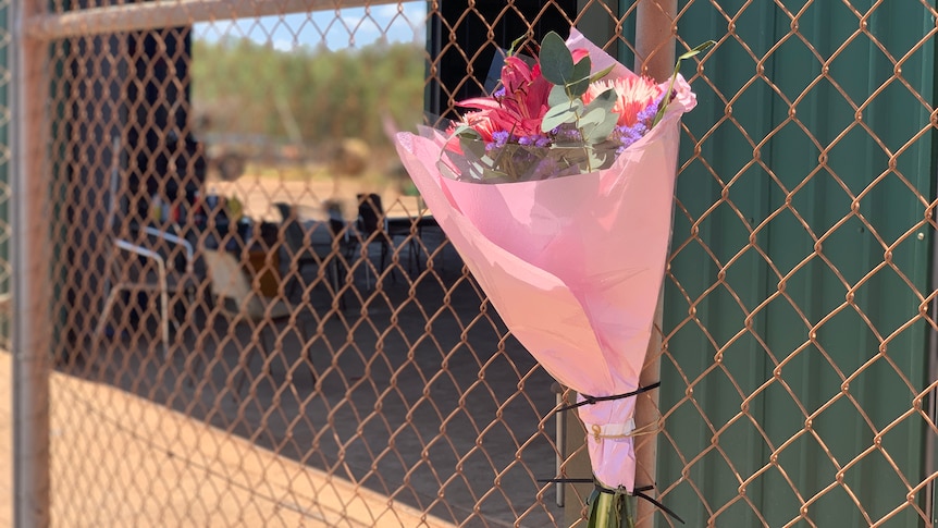 A close-up shot of a bouquet of flowers tied to a fence.