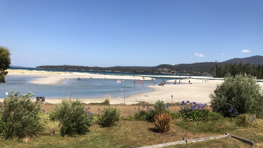 A fenced off beach area with people playing in the distance