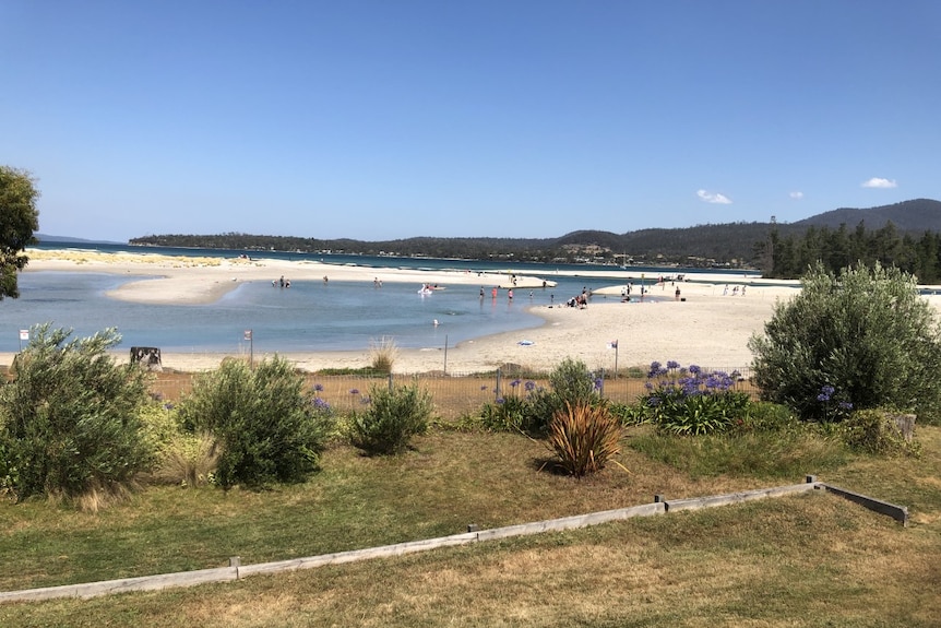 A fenced off beach area with people playing in the distance