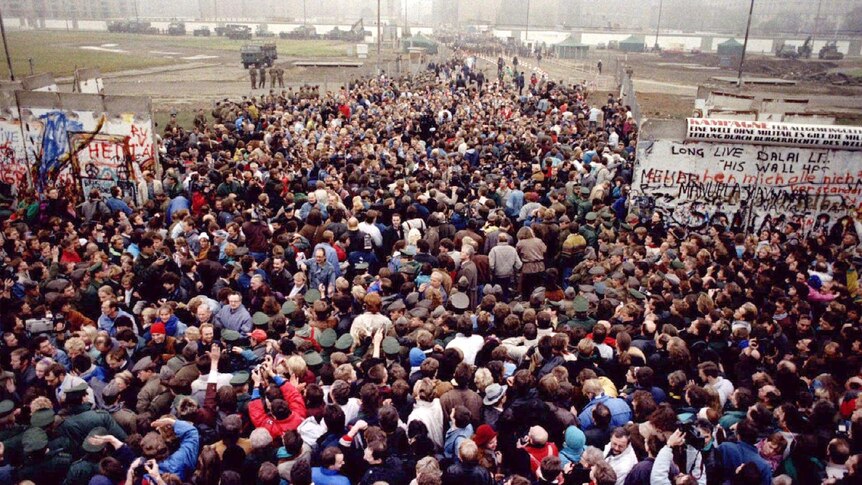 Two crowds of people meet after a large part of the Berlin Wall is opened