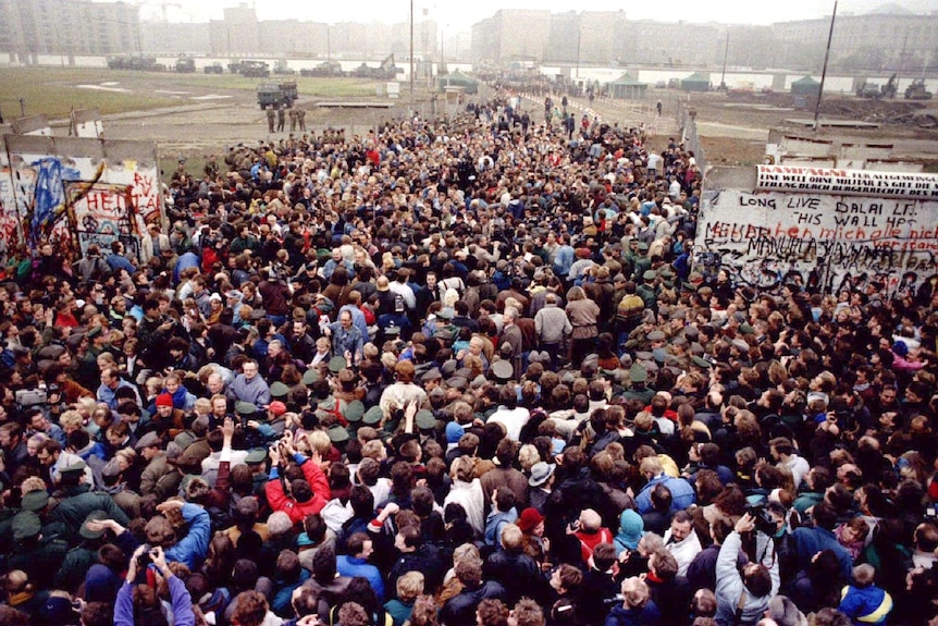 Two crowds of people meet after a large part of the Berlin Wall is opened