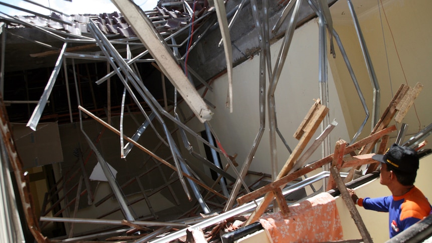 An Indonesian rescue official looks at the collapsed roof of a shop in Denpasar