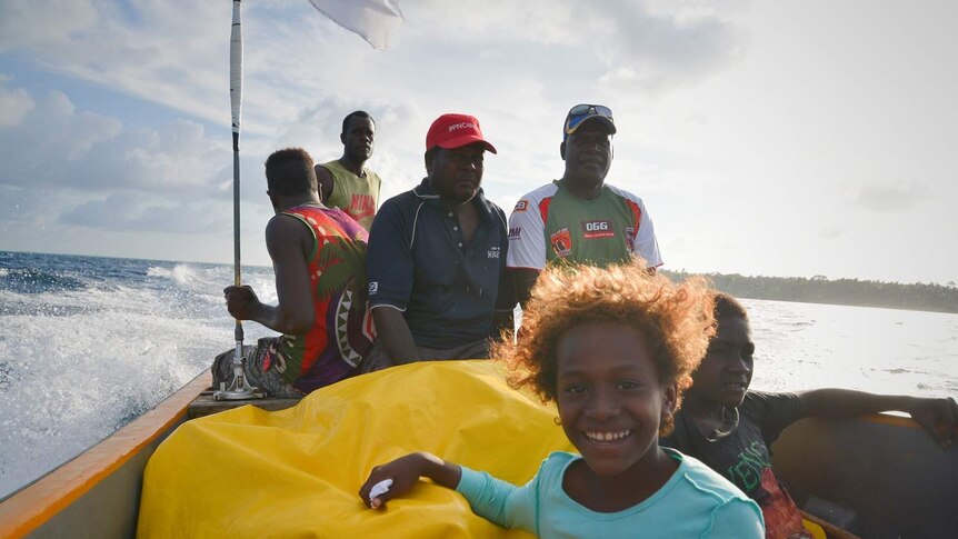 Child smiles on a boat with a group of adults