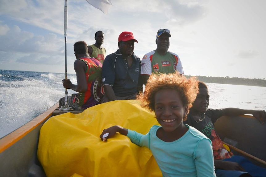 Child smiles on a boat with a group of adults