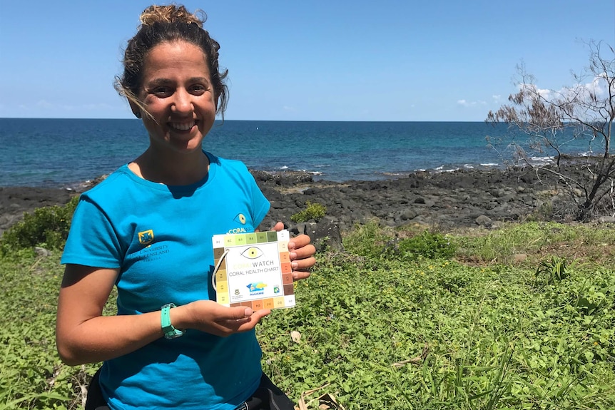 Natalie Lobartolo holding a coral health chart.