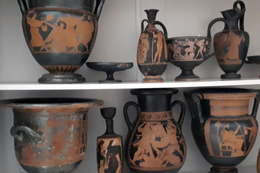 Eight historic vases sit on two shelves