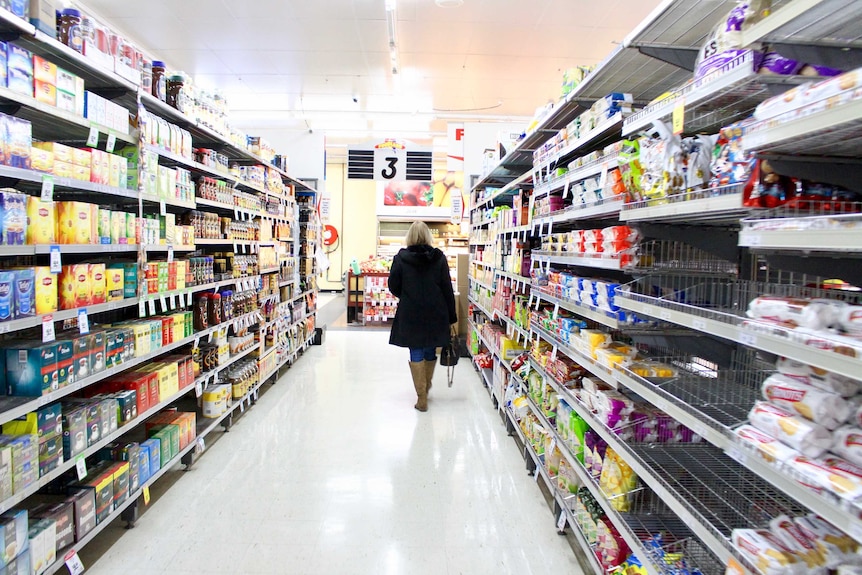 woman walks through supermarket aisle
