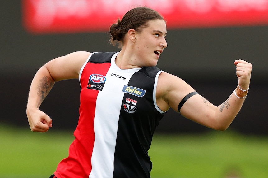 A St Kilda AFLW player pumps her fist as she celebrates a goal.