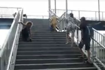 A man without legs climbs up a steep flight of stairs at a train station.