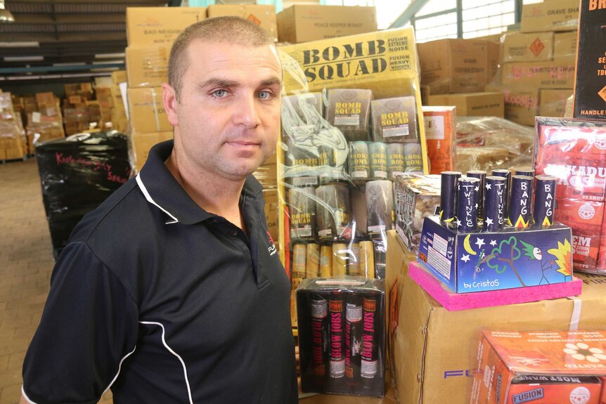 Luke Caridi stands in a warehouse full of fireworks.