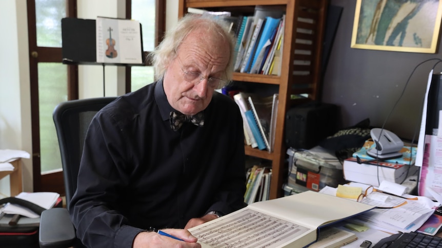 a man in his 60s pores over Mozart manuscripts