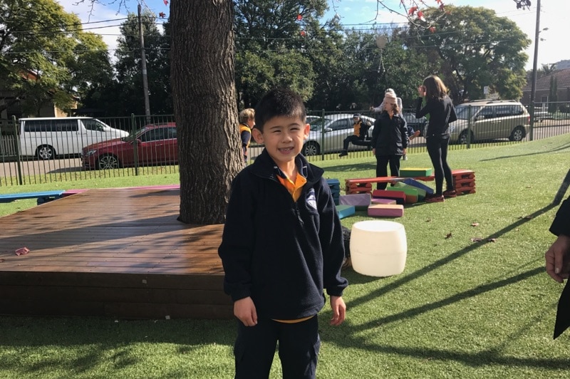 7 year old James smiles for the camera while playing during recess at Giant Steps School