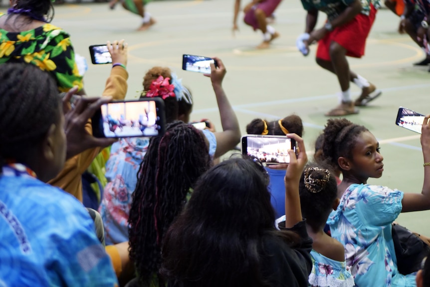 Group of people holding phones up filming island dancing