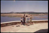 People stand at what is now Regatta Point, watching Lake Burley Griffin fill.