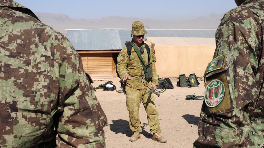 Afghan National Army soldiers watch Australian Sergeant David Nicholls as he demonstrates explosives search techniques.
