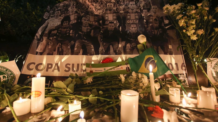 A Chapecoense soccer team poster stands behind flowers and candles left by soccer fans in Bogota.