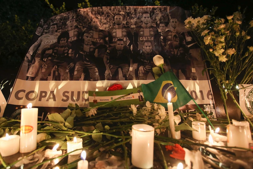 A Chapecoense soccer team poster stands behind flowers and candles left by soccer fans in Bogota.